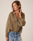 Woman wearing a patterned blouse and jeans against a plain background