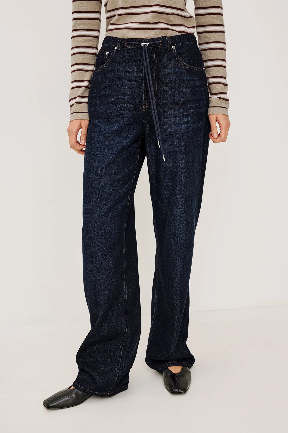 denim tie waist pant worn by a model with a stripe shirt on a grey background