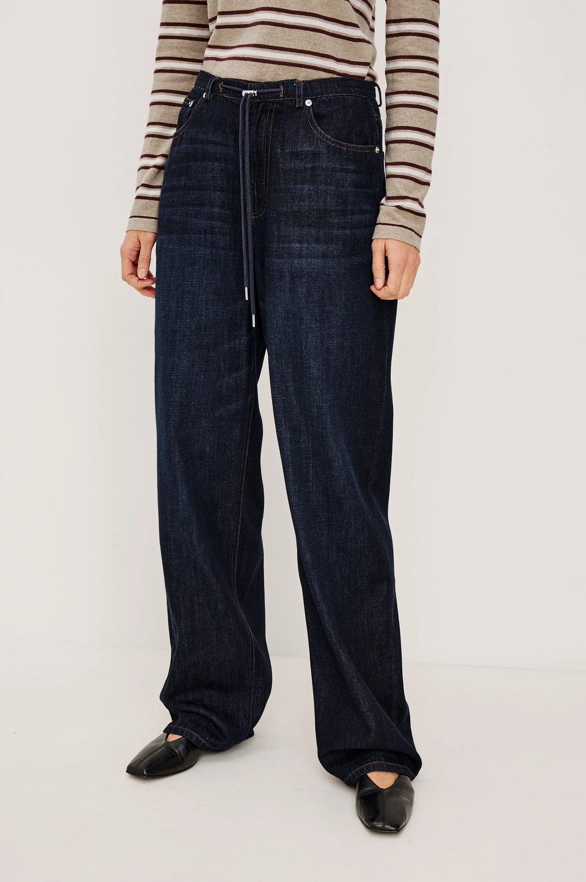 denim tie waist pant worn by a model with a stripe shirt on a grey background