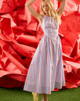 Woman in a striped dress standing in front of a large red flower-like structure.