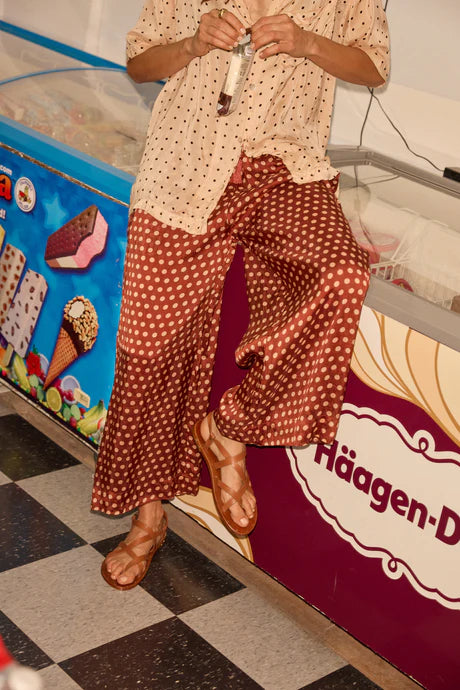 Person wearing a patterned outfit standing in front of an ice cream freezer with 'Haagen-Dazs' branding. close up on pant