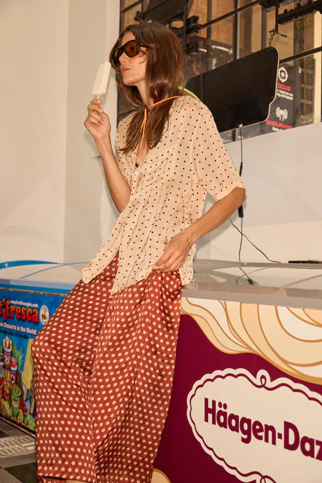 Woman in a polka dot outfit standing in front of a Häagen-Dazs display.