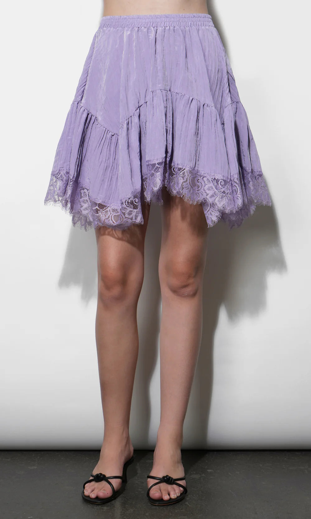 Person wearing a light purple lace-trimmed skirt on a plain background