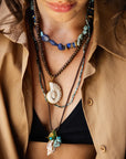 Close-up of a person wearing multiple necklaces with a beige jacket.
