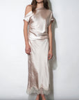 A woman modeling a champagne satin two-piece set consisting of a cold-shoulder top and a matching midi skirt with a lace hem, set against a plain white studio background.