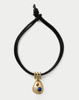 Black cord necklace with a gold pendant featuring a blue gemstone on a white background