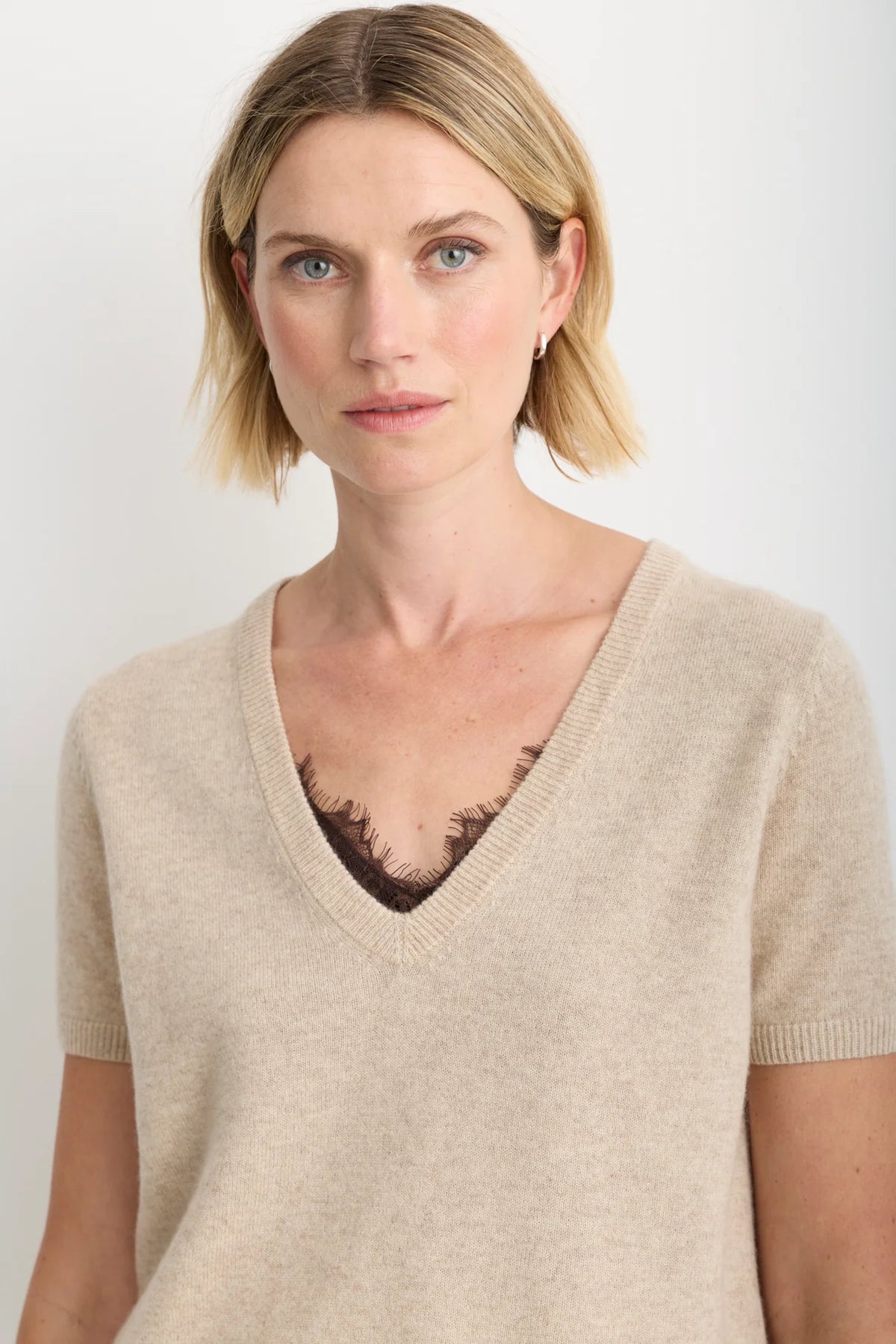model wearing a oatmeal short sleeve sweater over a brown lace top 