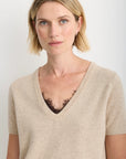 model wearing a oatmeal short sleeve sweater over a brown lace top 