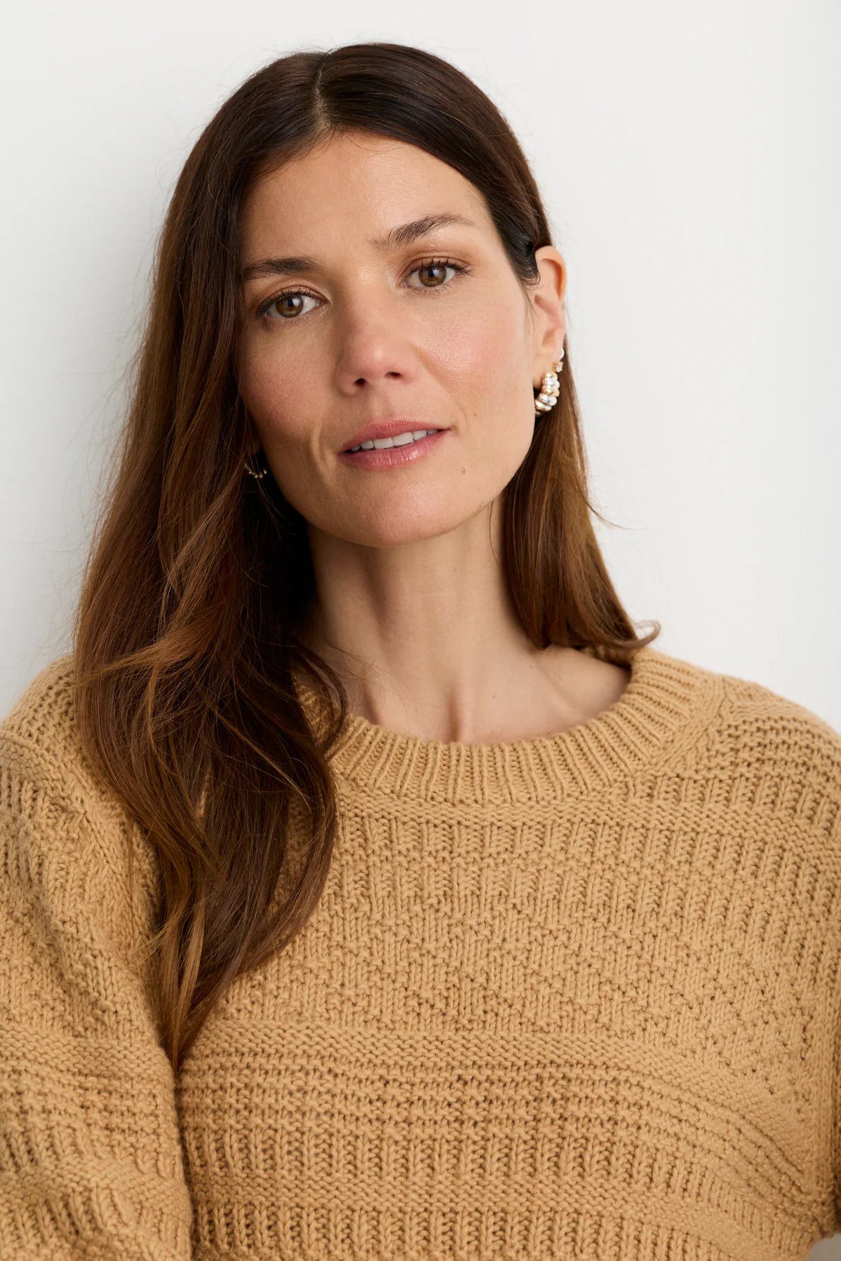 model wearing a tan sweater on a white background