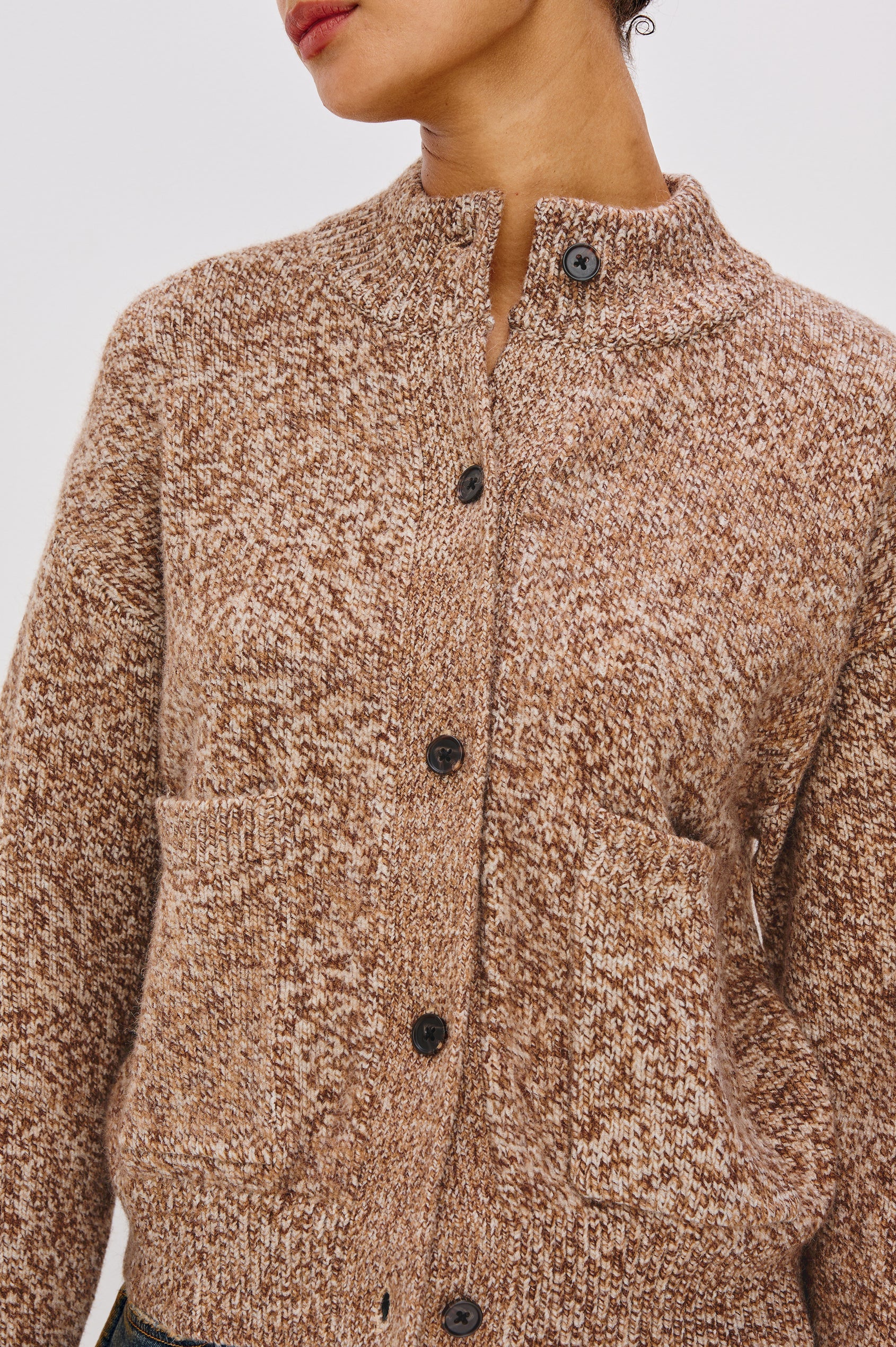 Close-up of a brown textured cardigan with black buttons on a light gray background