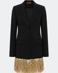 A black tailored blazer with a single front button, notched lapels, flap pockets, and a contrasting gold fringe hem, shown on a light gray background.