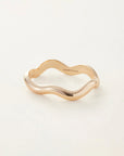Gold ring with wavy design on a white background, branded 'Jenny Bird'.