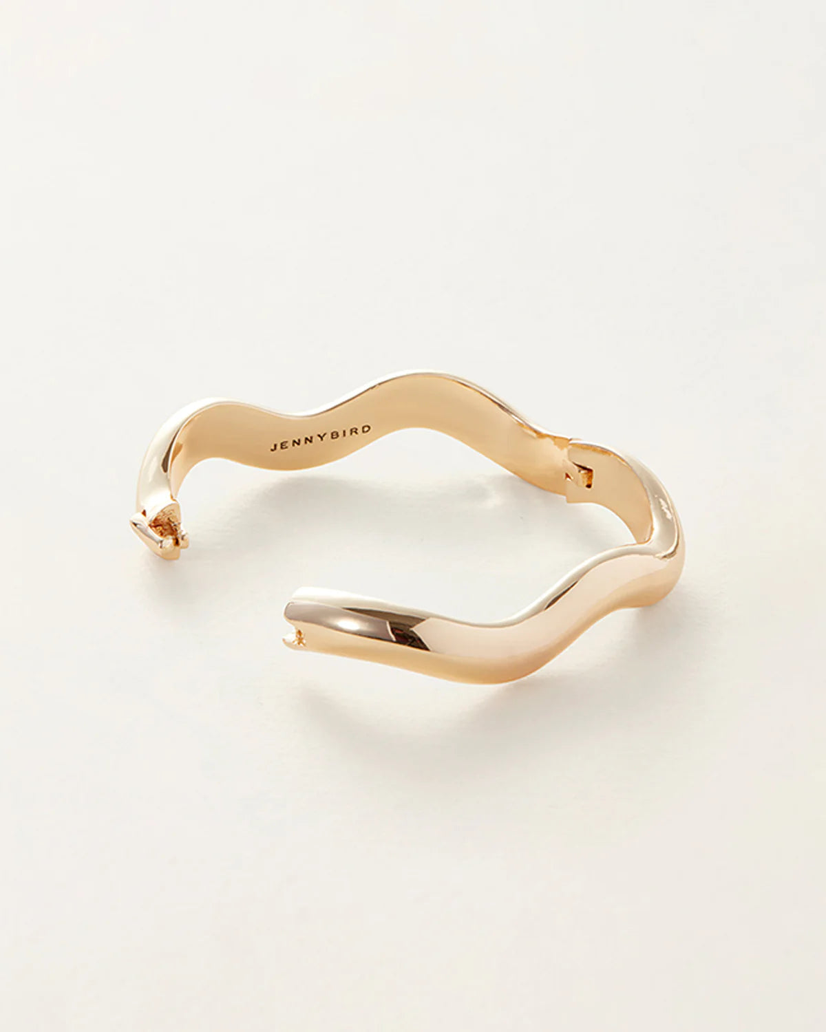 Gold bracelet with 'Jenny Bird' engraving on a light beige background