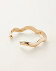 Gold bracelet with 'Jenny Bird' engraving on a light beige background