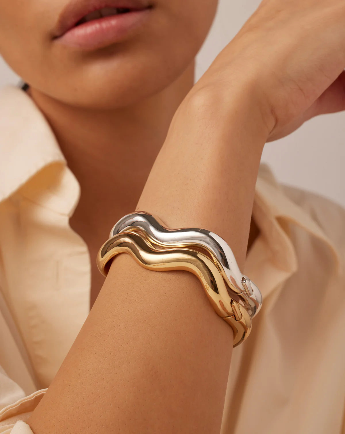 Gold and silver bracelet on a person's wrist with a neutral background