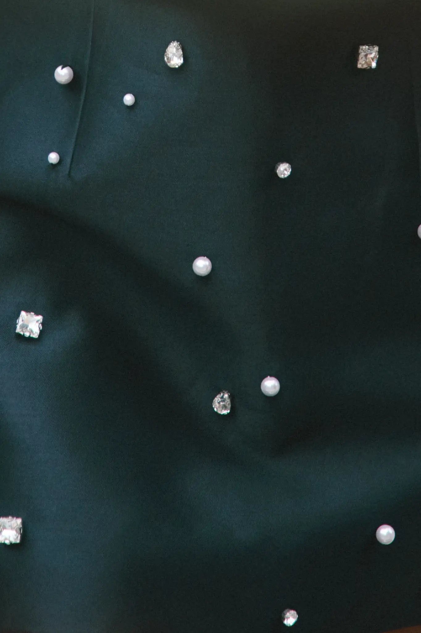 Close-up of black fabric with small decorative stones and pearls.