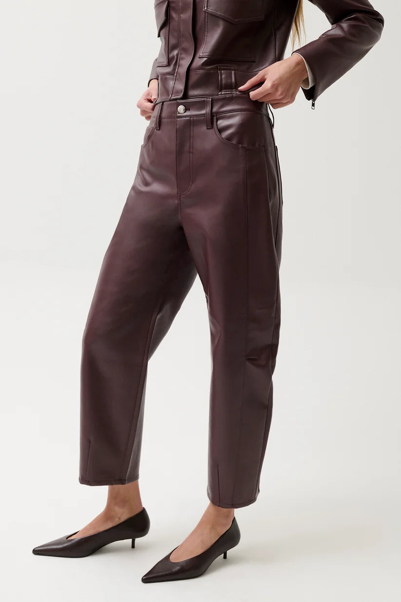 A model wearing dark brown faux leather cropped pants with a matching jacket and black pointed-toe kitten heels, shown from the waist down against a light gray studio background.