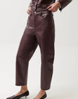 A model wearing dark brown faux leather cropped pants with a matching jacket and black pointed-toe kitten heels, shown from the waist down against a light gray studio background.