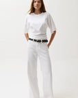 Woman wearing a white t-shirt and pants with a black belt on a white background