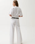 Person wearing a white outfit with a belt on a plain background