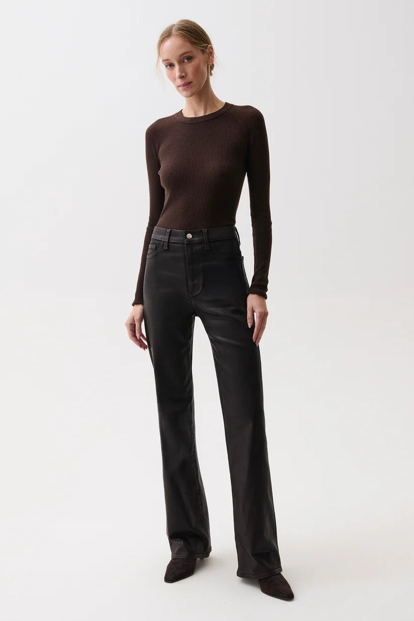 A woman modeling a dark brown long-sleeve crewneck top and black wide-leg jeans against a plain light gray studio background.