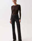 A woman modeling a dark brown long-sleeve crewneck top and black wide-leg jeans against a plain light gray studio background.