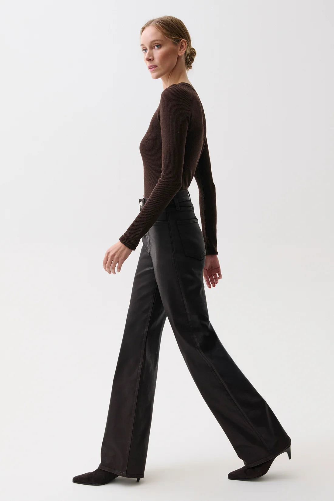 A woman modeling a dark brown long-sleeve knit top and black wide-leg trousers against a clean white studio background.