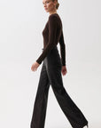 A woman modeling a dark brown long-sleeve knit top and black wide-leg trousers against a clean white studio background.