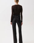 A model viewed from the back wearing a dark brown long-sleeve top and black wide-leg trousers, standing against a plain white studio background.