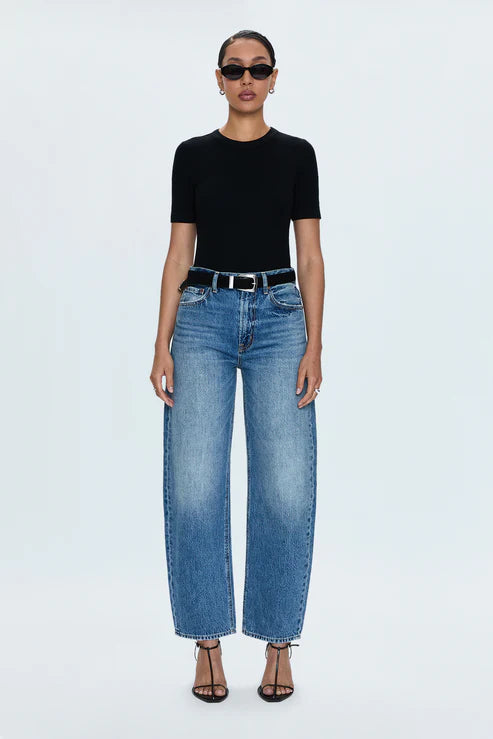 Woman wearing a black top and blue jeans on a white background