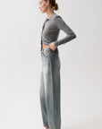 model wearing a rhinestone blue jean with a long sleeve grey top on a white background, side view
