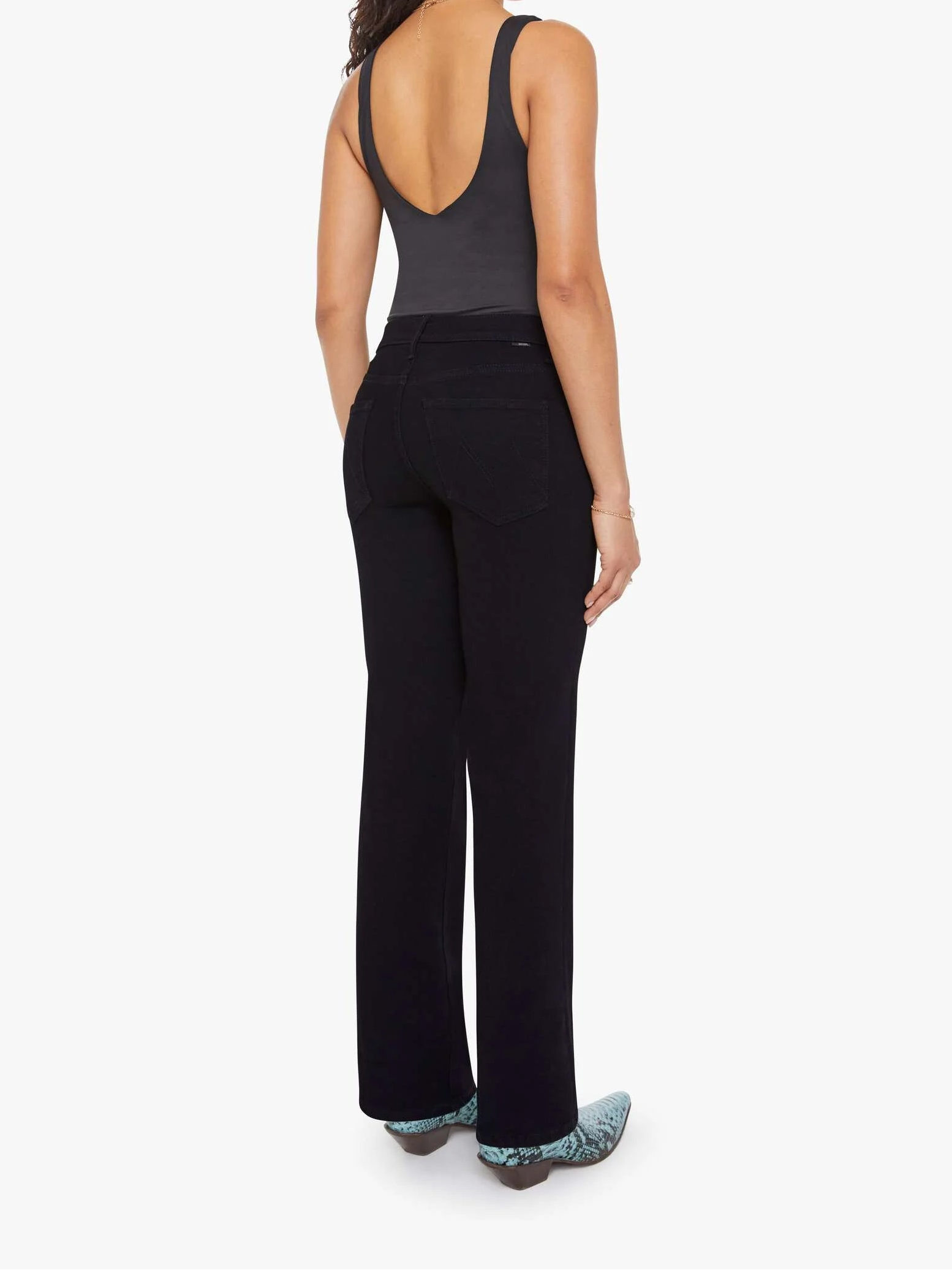 Woman wearing a black sleeveless top and black pants on a white background