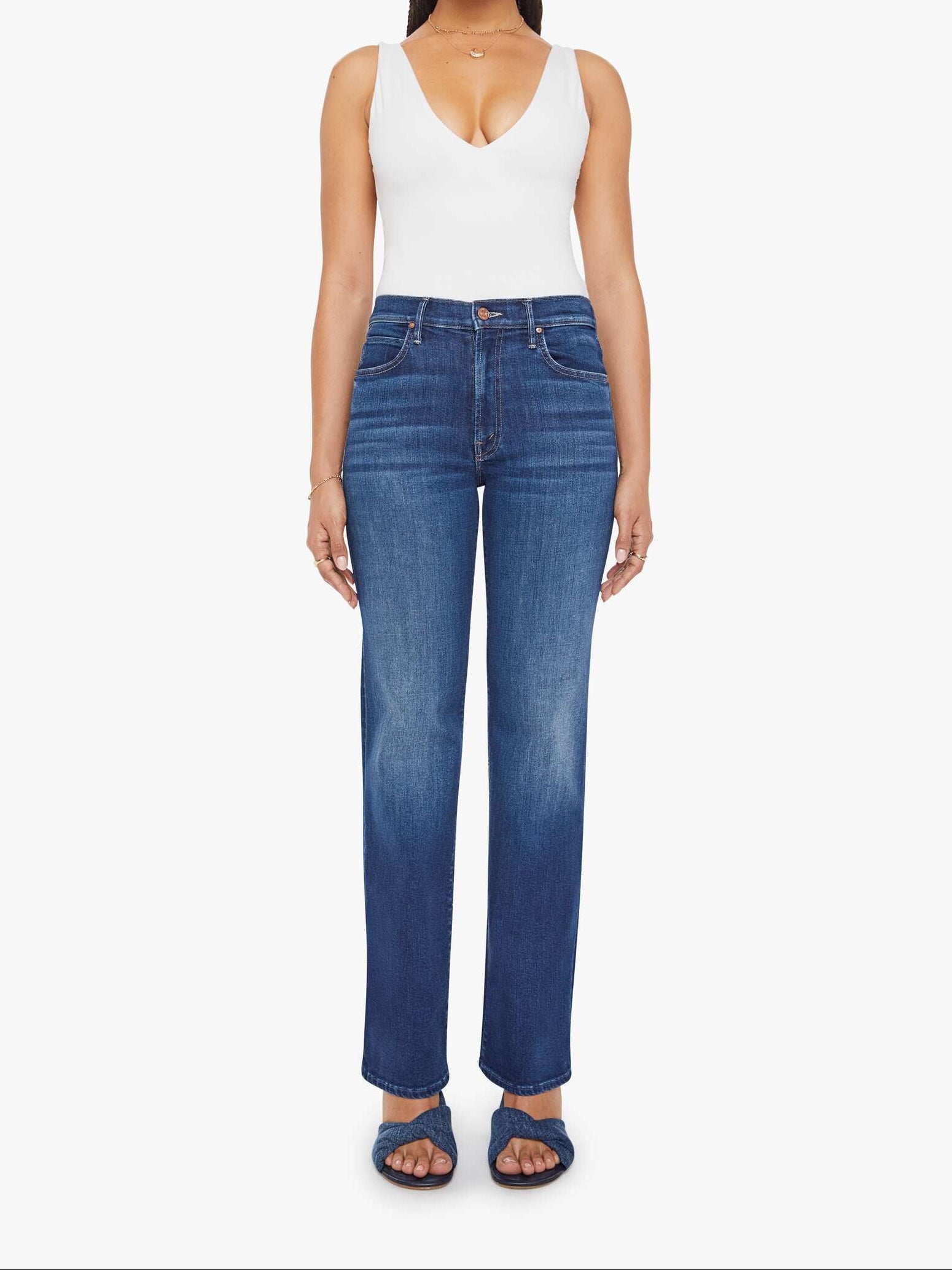 Woman wearing a white tank top and blue jeans on a white background