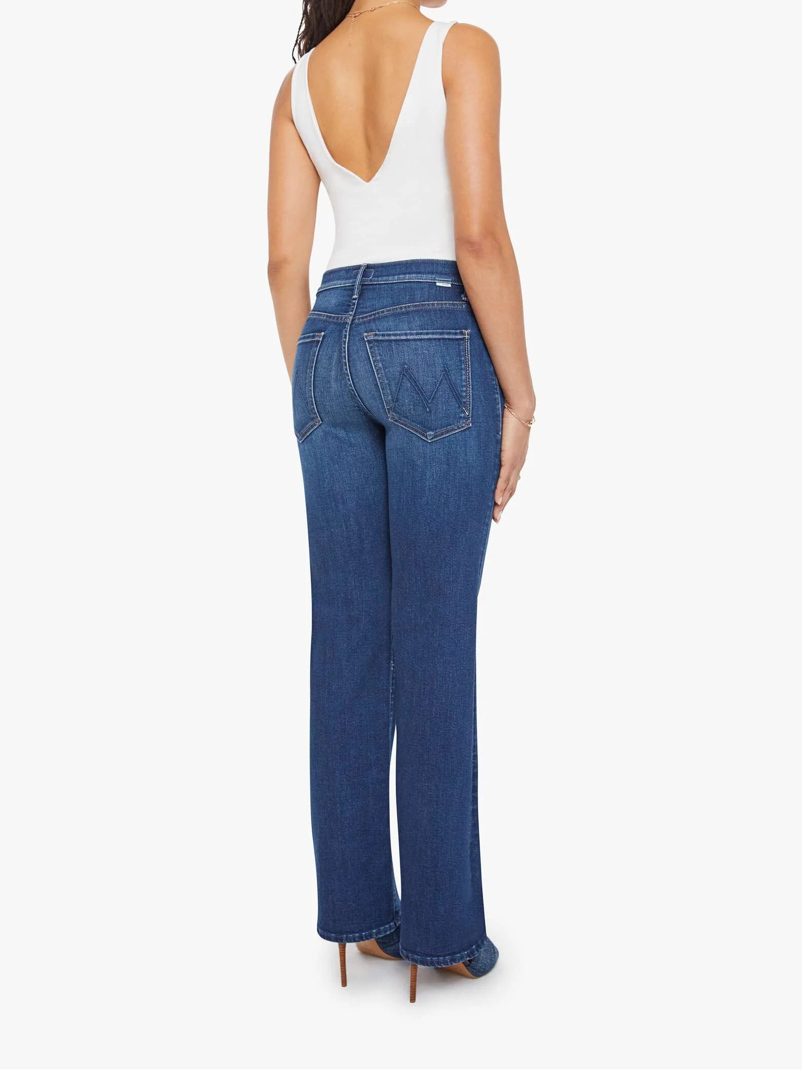 Woman wearing blue jeans and a white top on a white background, back view