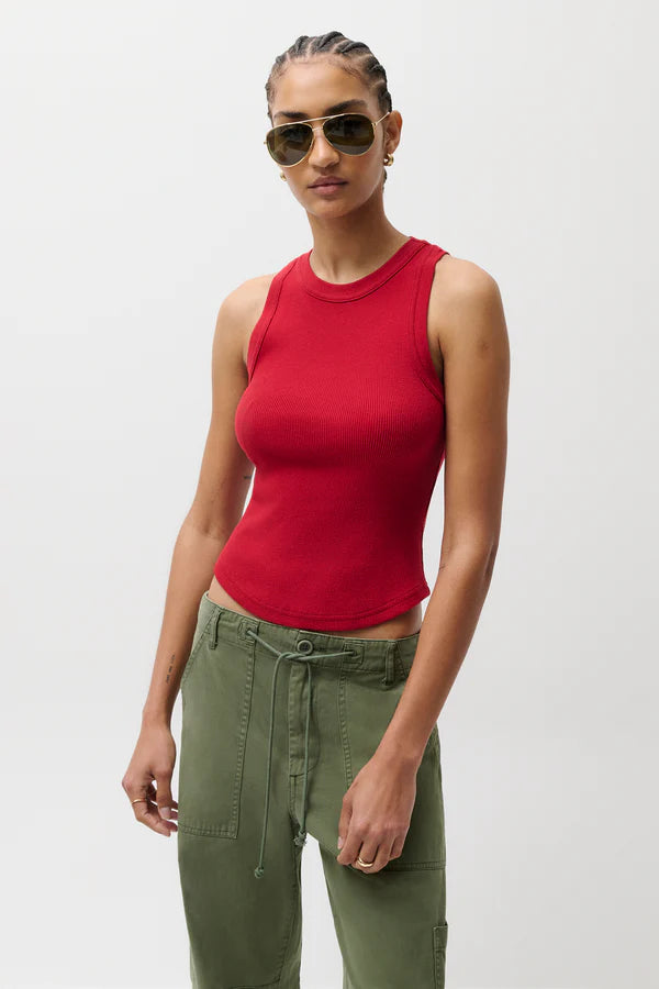 Person wearing a red sleeveless top and green pants on a white background