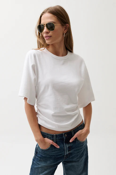 Woman wearing a white t-shirt and blue jeans with sunglasses on a plain background