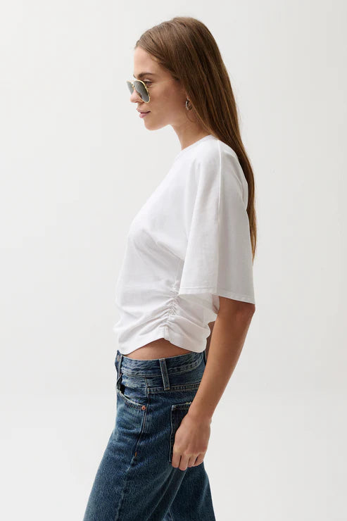 Woman wearing a white t-shirt and blue jeans against a plain background