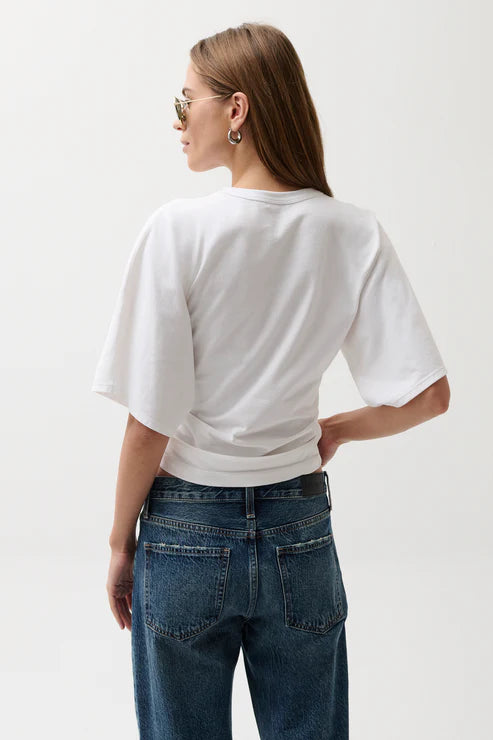 Person wearing a white t-shirt and blue jeans on a plain background