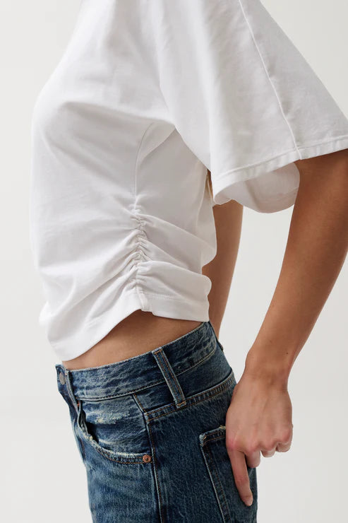 Person wearing a white oversized shirt and blue jeans on a plain background