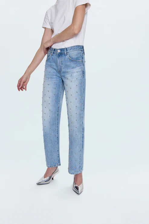 Person wearing light blue jeans with studs and a white shirt on a white background