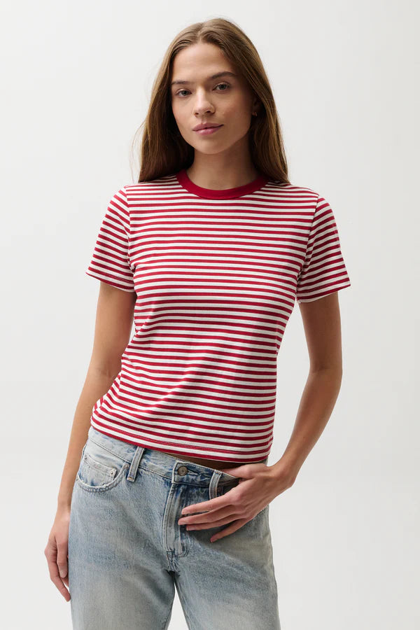 Woman wearing a red and white striped shirt with blue jeans on a plain background