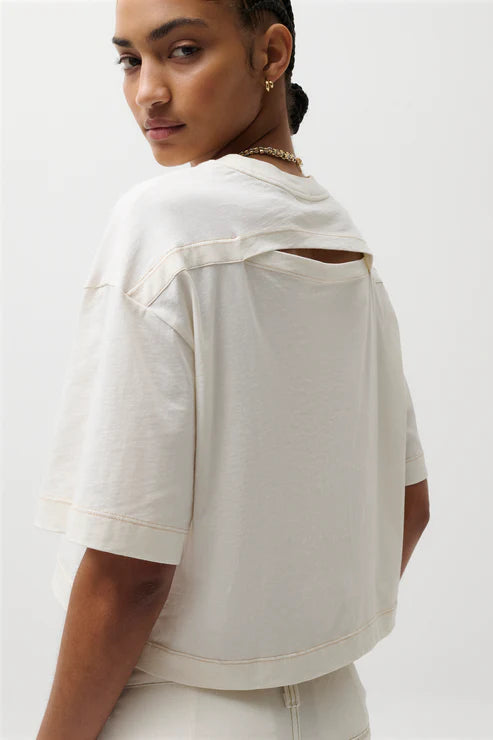 Woman wearing a light-colored top with cut-out design on a white background