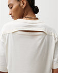Person wearing a white blouse with a plain background, back