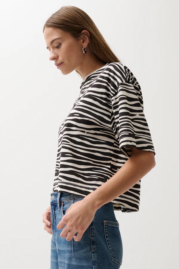 Woman wearing a black and white zebra-striped shirt against a plain background