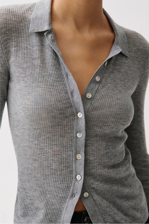 A close-up of a person wearing a gray ribbed long-sleeve button-up shirt with a pointed collar and white buttons.