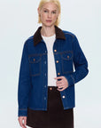 Woman wearing a blue denim jacket with a white shirt and black skirt on a light gray background