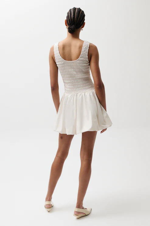 Person wearing a white dress on a plain background, back
