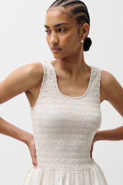 Woman wearing a white sleeveless against a plain background
