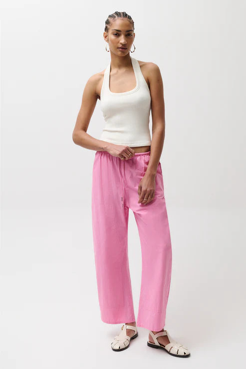 Woman wearing a white tank top and pink pants on a white background
