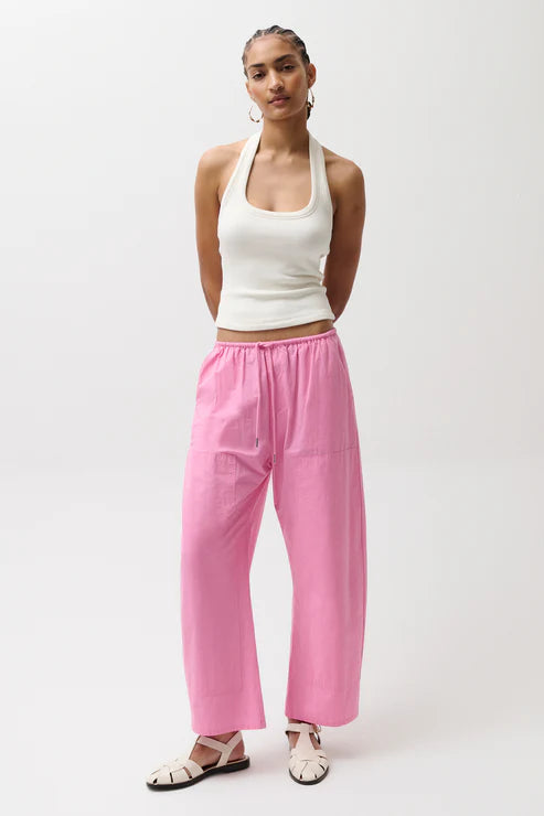 Woman wearing a white top and pink pants on a white background